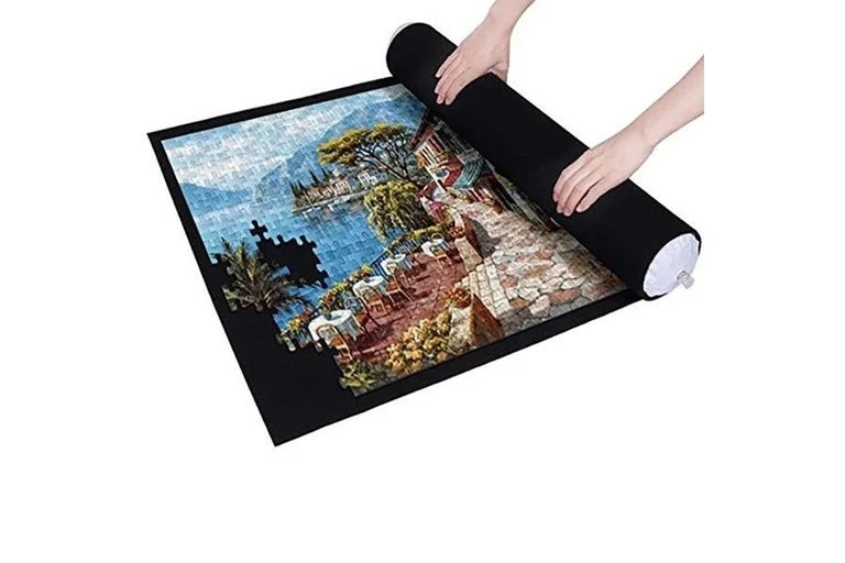 Hands rolling a black puzzle mat around a partially assembled scenic jigsaw
puzzle.